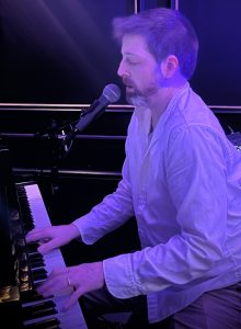 a man playing piano with microphone blue lighting 