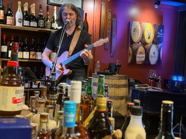 Tom Campbell having fun behind bottles at Market Alley Wines